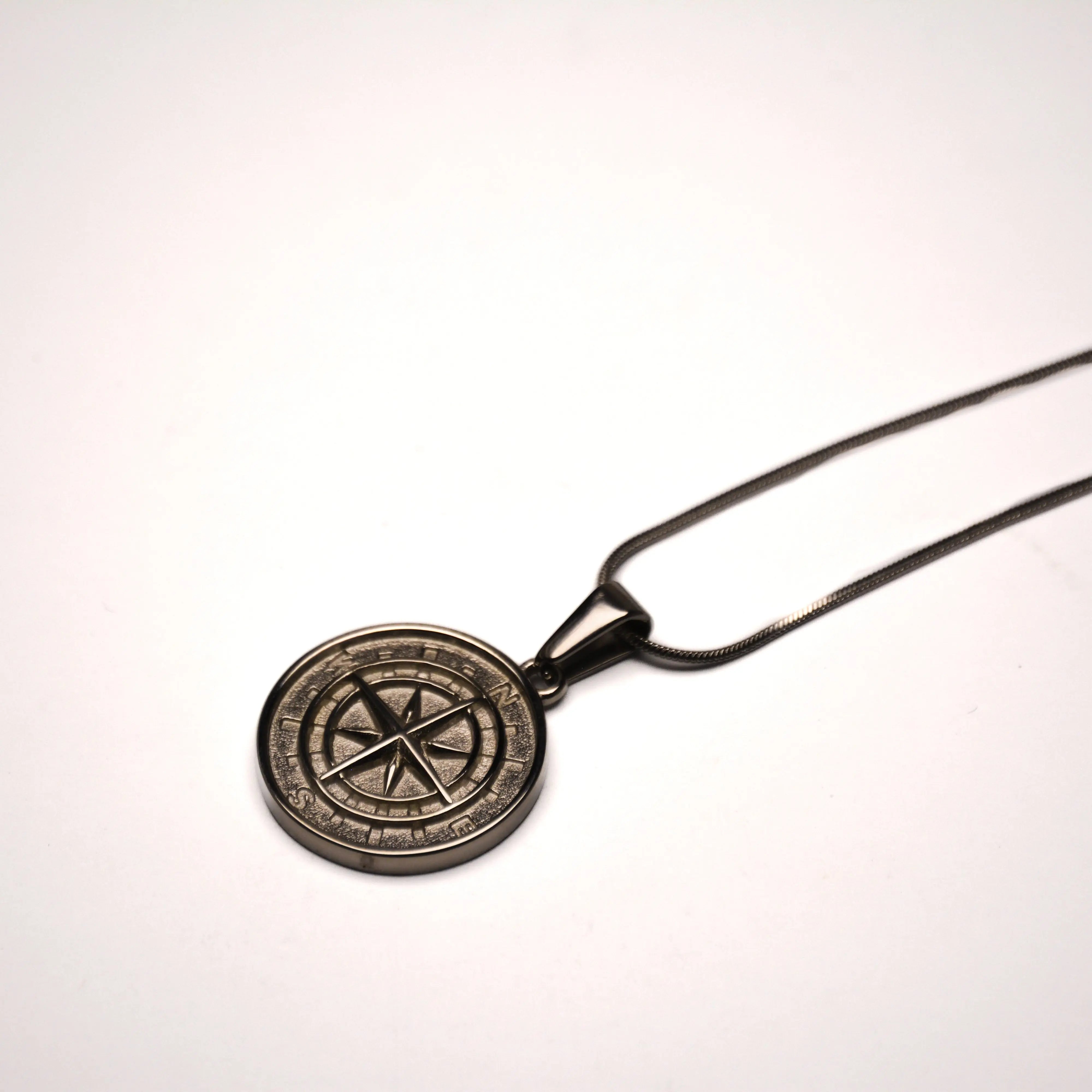 "A silver compass pendant with a small magnetic needle, symbolizing direction and navigation."